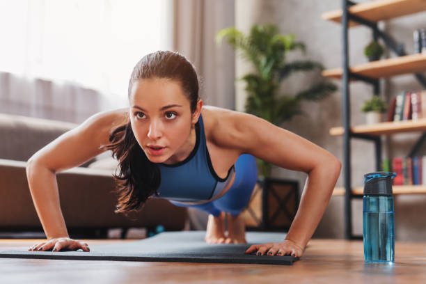 beautiful young sports lady doing push ups while workout at home wellness tips for women practicing self-care